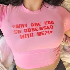 a woman laying in bed wearing a pink shirt that says, why are you so obsesed with me?