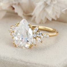 an engagement ring with a pear shaped diamond surrounded by small white and yellow diamonds on top