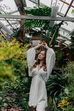 a woman standing in a greenhouse with her hands on her head