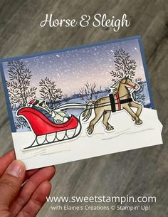 a hand holding up a card with a horse and sleigh on it