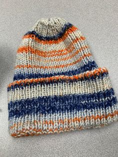 Adult size hat, knit in single rib with acrylic yarn. Hat has a folded brim and is washer and dryer friendly. White blue and orange color Stripe Knit Hat Pattern, Striped Beanie Knitting Pattern, Multicolor Knit Beanie, One Size Fits Most, Knit Outdoor Hat, One Size Fits Most, Multicolor Brimmed Knitted Beanie, Outdoor Knitted One-size Beanie, Ribbed Hat, Colorful Hat, Hat Knit