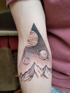 a person with a tattoo on their arm that has an image of saturn and mountains