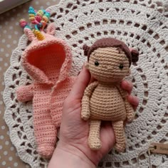 a small crocheted doll sitting on top of a doily next to a stuffed animal