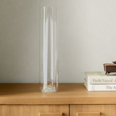 a glass vase sitting on top of a wooden table next to books and a chair