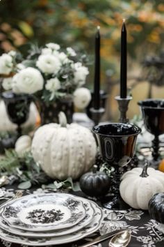 a black and white table setting with pumpkins