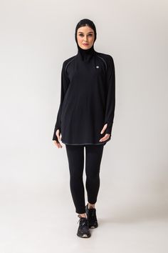 Relaxed fit hooded athletic tunic in high-stretch brushed nylon. Long sleeves with high zipped funnel neck. Fitted 'hijab' hood can be secured at the neck with the 1/4 zip. Curved hem with side slits for ease of movement. Thumbholes and hidden side pockets.   Complete your look with Lanuuk Active Leggings or Lanuuk Active Joggers.  -4way stretch -Breathable -Moisture absorbing -Sweat releasing -Quick-drying  This comprises a capsule collection of activewear pieces designed with modesty and ease Technical Long Sleeve Activewear For Winter, Black High Neck Athleisure Activewear, Long Sleeve Training Hoodie, Technical Long Sleeve Activewear With Drawstring Hood, Black Long Sleeve Training Hoodie, Winter Techwear Long Sleeve Activewear, Long Sleeve Activewear With Drawstring Hood For Training, Technical Stretch Hooded Activewear, Stretch Funnel Neck Hoodie In Athleisure Style