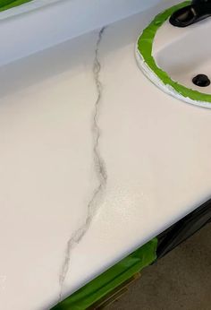 a close up of a sink with a green brush on it's edge and a hole in the counter