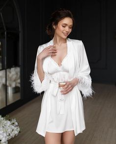 Make your bridal party feel luxurious and pampered with our White Feather Bride Robe Set! Each set includes delicate bridesmaid robes with a matching nightdress for the bride. The bride's nightgown and robe feature stunning feather sleeves for a touch of glamour. This elegant and stylish set makes the perfect bridesmaid gift to show your appreciation for your closest friends on your special day. Let your bridal party relax in style and comfort with this sophisticated White Feather Bride Robe Set Long Sleeve Feather Robe For Parties, Wedding Satin Robe With Feathers, Feathered Robe For Wedding Night, Elegant Satin Robe With Feathers, Elegant Robe With Feather Trim For Wedding Night, Elegant Party Robe With Feather Trim, Elegant Long Sleeve Bridesmaid Sleepwear, Elegant Feather Trim Dress For Wedding Night, Elegant Wedding Robe With Feathers