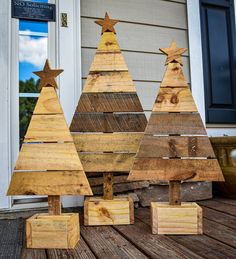 three wooden christmas trees sitting on top of a porch