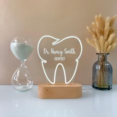 a wooden stand with a tooth and an hourglass next to it on a table