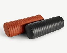 two black and brown leather objects on a white background, one is rolled up to the side