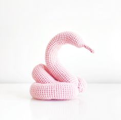 a pink knitted snake sitting on top of a white table