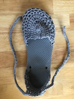 a gray crocheted bag sitting on top of a wooden floor next to a pair of scissors