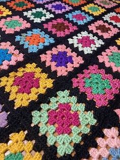 a multicolored crocheted blanket with flowers on it