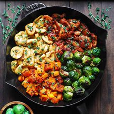 an iron skillet filled with different types of pasta and veggies on top of a wooden table