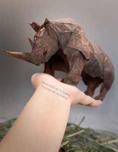 an origami rhinoceros is on someone's hand, with the words underneath it