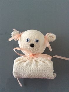 a white teddy bear wrapped in a blanket with pink ribbon around it's neck