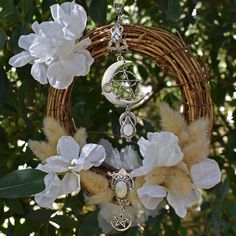 a wicker wreath with white flowers hanging from it's sides and a crescent