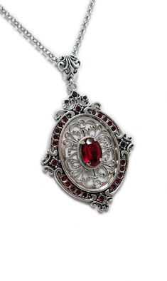 This gorgeous pendant is made with a large antiqued silver plated openwork filigree frame, adorned with over 2 dozen dazzling DARK RUBY RED glass rhinestones that perfectly surround a larger jewel in the center. Pendant has substantial weight, measuring 3" tall (including the decorative bail) and 2" wide, and is worn on a sturdy rolo chain in your choice of length.This is available in a variety of stone colors in our store, along with matching earrings. If you don't see something with the stone Raw Carnelian, Filigree Frame, Victorian Filigree, Goth Steampunk, Red Gothic, Tooth Necklace, Carnelian Necklace, Gothic Victorian, Choker Pendant