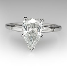 a pear shaped diamond engagement ring with three baguets on the side and shoulders