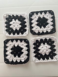 four black and white crocheted coasters sitting on top of a table