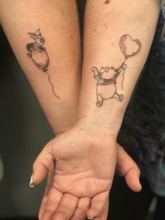 two people with tattoos on their arms holding hands and one has a balloon attached to the arm