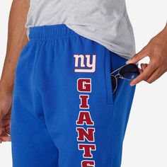 Show your true colors while crushing it in the gym or crushing a nap at home in these New York Giants Team Color Sweatpants. Features All-over, team-colored design so you can rep the team in style Team logo display on upper left leg, in case there were any doubts where your allegiances lie Vertical, stacked and team-colored team wordmark display on left leg so you can show off your team pride with every stride Elastic waistband to keep you comfortable Details Material: 65% Cotton/35% Polyester O Team-colored Bottoms For Game Day, Sporty Cotton Bottoms For Game Day, Athleisure Activewear For Team Events And Sports Season, Athleisure Activewear For Sports Season And Team Events, Athleisure Activewear For Team Events, Blue Team Spirit Sports Bottoms, Team-colored Casual Bottoms For Sports Events, Casual Team-colored Bottoms For Sports Events, Sportswear Joggers For Sports Events And Season