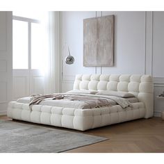 a white bed sitting on top of a hard wood floor next to a large window