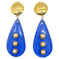 A striking pair of Vintage Vogue Bijoux Drop Earrings. Meticulously crafted the lavish blue teardrop adorned with half pearls is a breathtaking style statement from this exquisite jewel House. The Italian jewellery brand Vogue Bijoux spans about four decades up until the 1990s. The company produced high quality, exceptionally designed handcrafted costume jewellery for high-end stores and boutiques. Consequently their pieces are rare and highly prized. Vintage Condition: Very good without damage or noteworthy wear. Signed: Vogue Bijoux Materials: Gold plated metal, resin, simulated pearls Fastening: clip Approximate Dimensions: 8.2cm Established in 2016, this is a British brand that is already making a name for itself in the jewellery world both at home and internationally. My business has Teardrop Pearl Earrings, Pearl Vintage, Jewellery Brand, Italian Jewelry, Vintage Vogue, Vintage Jewels, Timeless Treasures, Style Statement, Vintage Jewellery