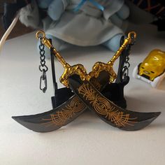 two swords are on top of each other in front of a toy yellow mask and chain