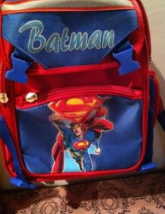 a back pack with the name batman printed on it and superman's caped head