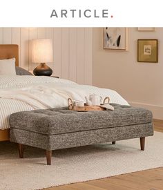 a bed sitting on top of a wooden floor next to a white rug and lamp