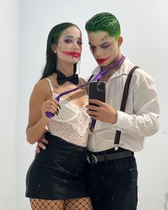 two people dressed up as clowns are looking at a cell phone