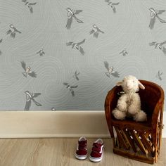 a stuffed animal sitting on top of a wooden chair in front of a wallpaper