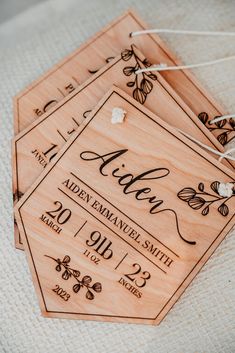 three wooden tags with names on them sitting on a white cloth covered tablecloths