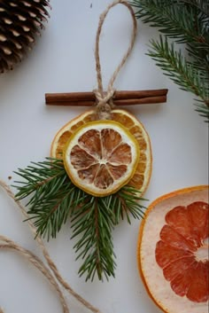 an orange cut in half sitting on top of a table next to pine cones and cinnamon sticks