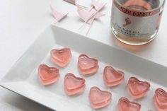 pink heart shaped candies on a white plate next to a bottle of booze