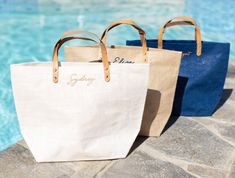 three canvas bags sitting next to a swimming pool