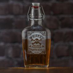 a bottle of whiskey sitting on top of a wooden table next to a brick wall