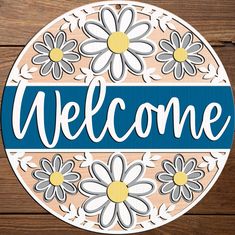 a sign that says welcome with daisies in the center on a wooden background,