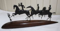 three black horse figurines sitting on top of a wooden board in front of a white wall