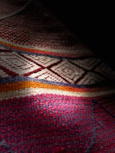 a close up view of a red, yellow and blue blanket on a bed with dark background