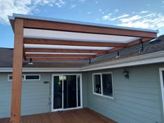 an outdoor patio with wooden decking and pergolated roof over the back door