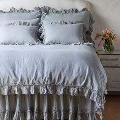 a white bed with ruffled sheets and pillows