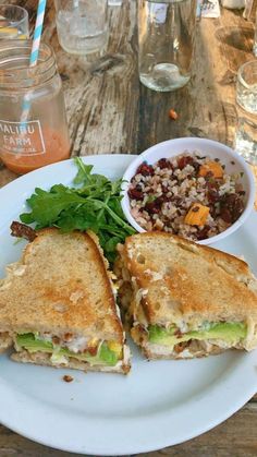 a white plate topped with a cut in half sandwich next to a bowl of salad