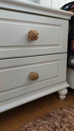 a white dresser with rope handles and knobs on it's drawers in a bedroom