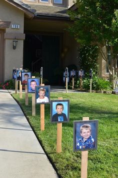 a group of wooden posts with pictures on them in front of a house and trees