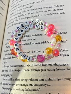 an open book with some beads on top of it and the words written in different languages