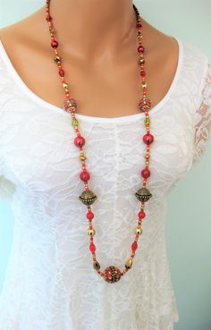 Red beaded woman's necklace handmade by Ralston Originals. Click to see this stunning red necklace with a variety of beads. This beautiful necklace is perfect to for a formal occasion, or for everyday. Red jewelry is perfect for the holidays too. This necklace is made with an assortment of beads. The focal bead at the bottom is a large red colored bead with detailed gold metal accents, and crystal rhinestones. There are two more similar beads in the necklace. The other beads include, crystal bea Red Beaded Necklaces, Long Necklaces, Hippie Necklace, Great Gifts For Women, Red Necklace, Red Jewelry, Necklace Red, Eyeglass Chain, Fish Hook Earrings