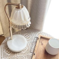 a table with a cup and saucer on it, next to a lamp shade